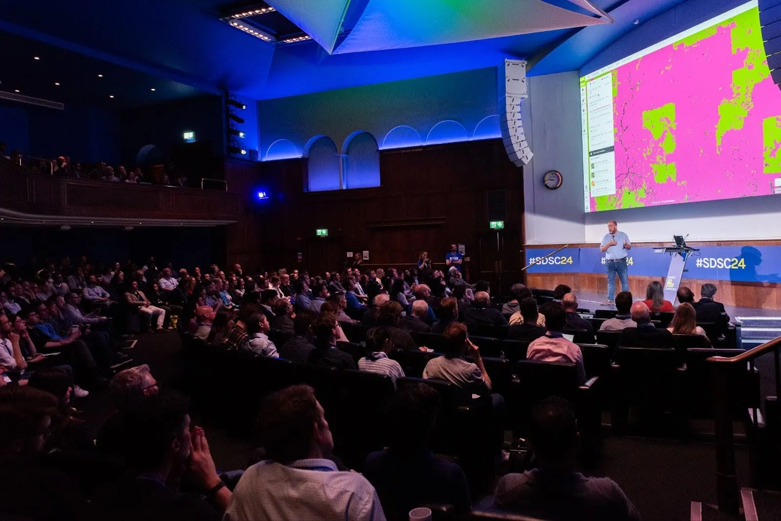 A photograph of a conference room with the keynote of SDSC24 being presented