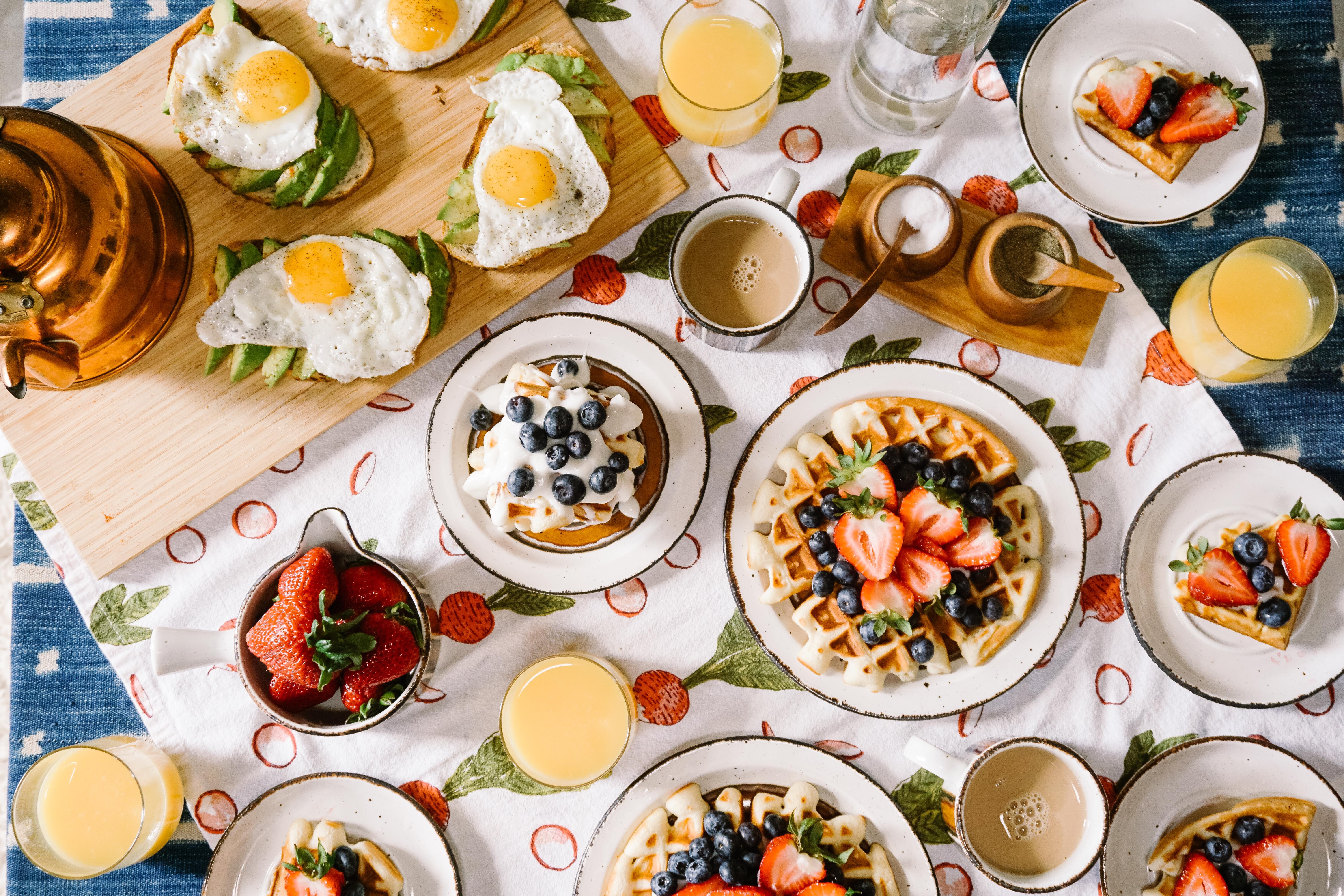 A photograph of a series of brunch items including tea, orange juice, waffles and pancakese